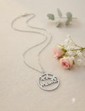 Collar plateado con colgante redondo calado con texto Mamá y flores