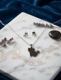 Conjunto de collar y pendientes de acero con silueta de gato plateada