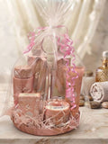 Cesta de regalo Yara en tonos rosa con presentación decorativa, lazo y toalla enrollada