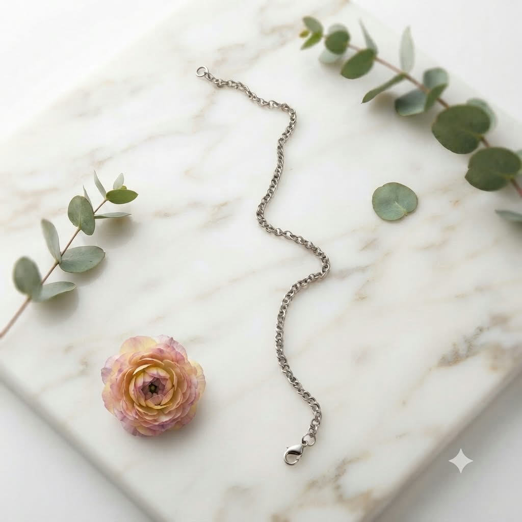 Pulsera eslabones finos acero inoxidable plateado sobre mármol con flor y eucalipto