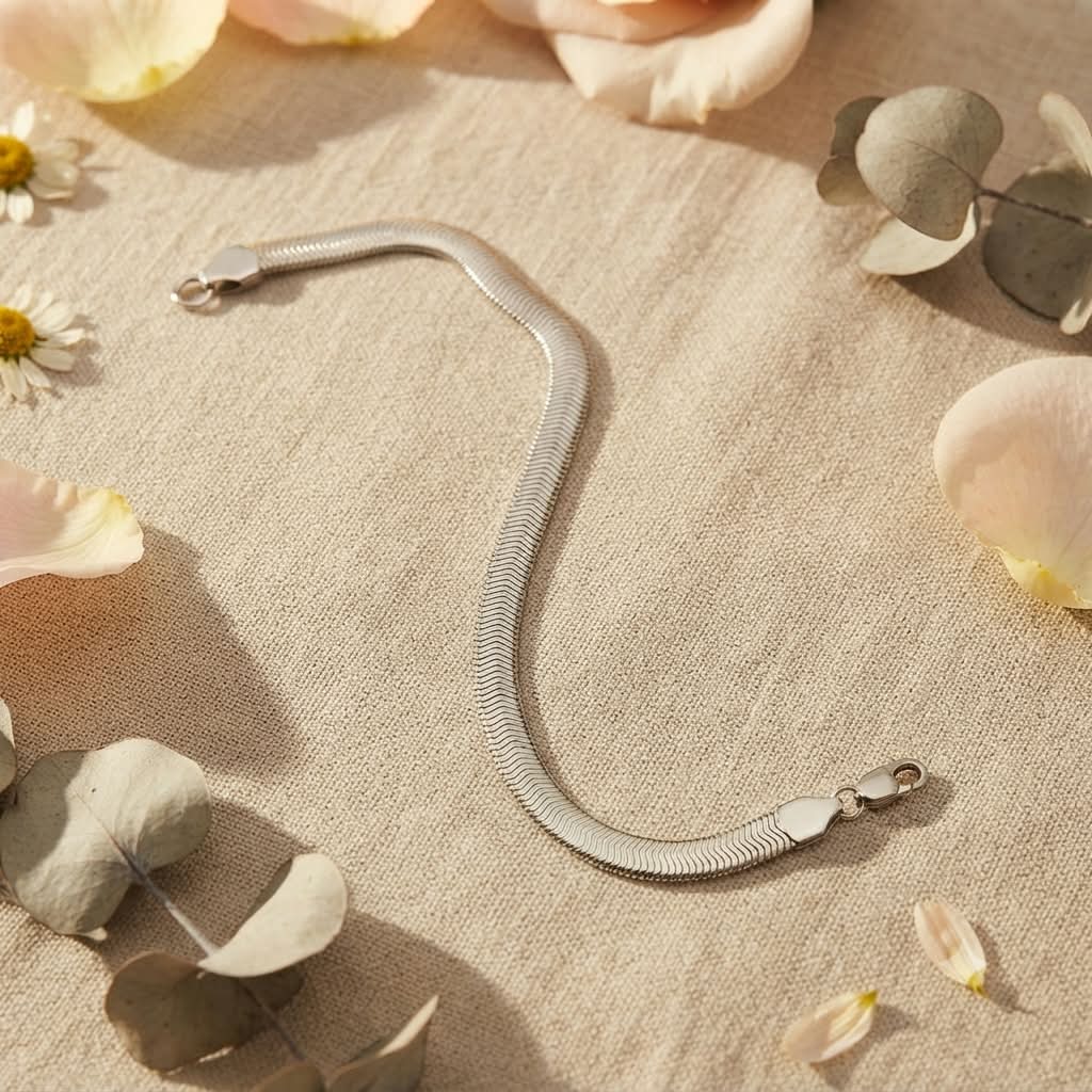 Pulsera plana tipo serpiente acero inoxidable plateado sobre tela beige con pétalos